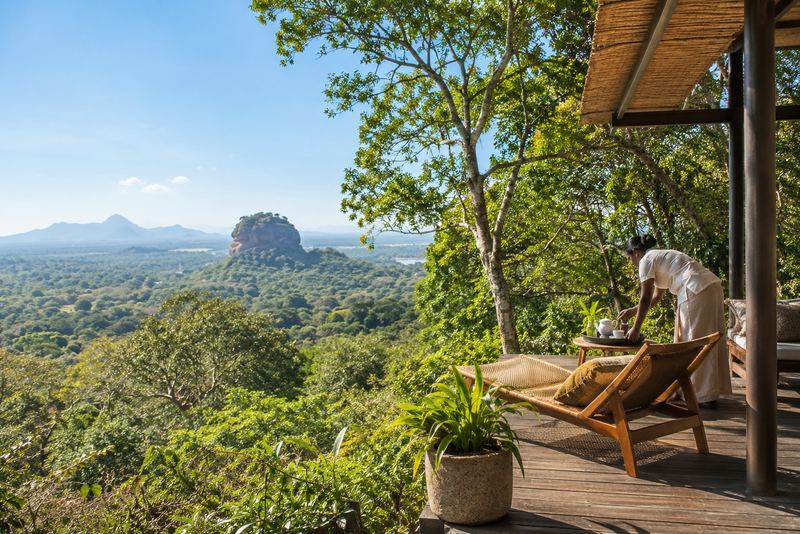 An eco-lodge veranda in morning sun with Sigiriya rock beyond