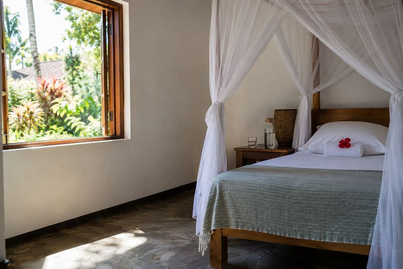 A spotless lodge guest room with a hibiscus on the pillow