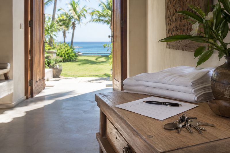 Villa keys, a checklist and fresh linen on a sunlit table
