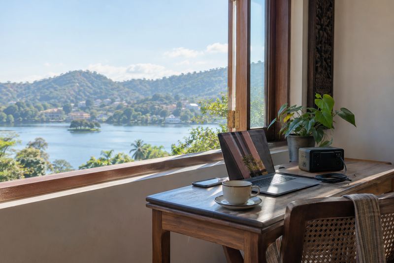 A work desk by an open window overlooking Kandy lake