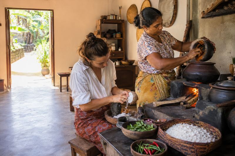 A cook and a visitor making curry in a sunny Kandy kitchen