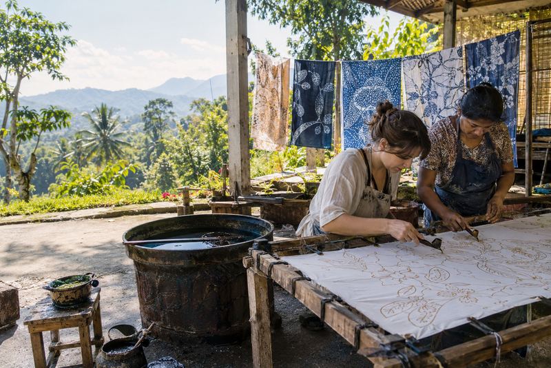 A visitor drawing wax on cotton at a sunny batik workshop