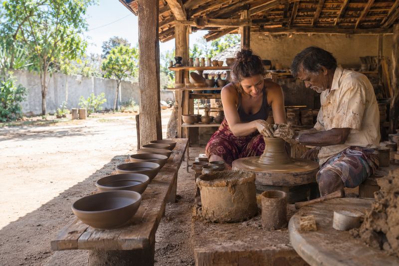 A potter and a visitor at the wheel in a village workshop