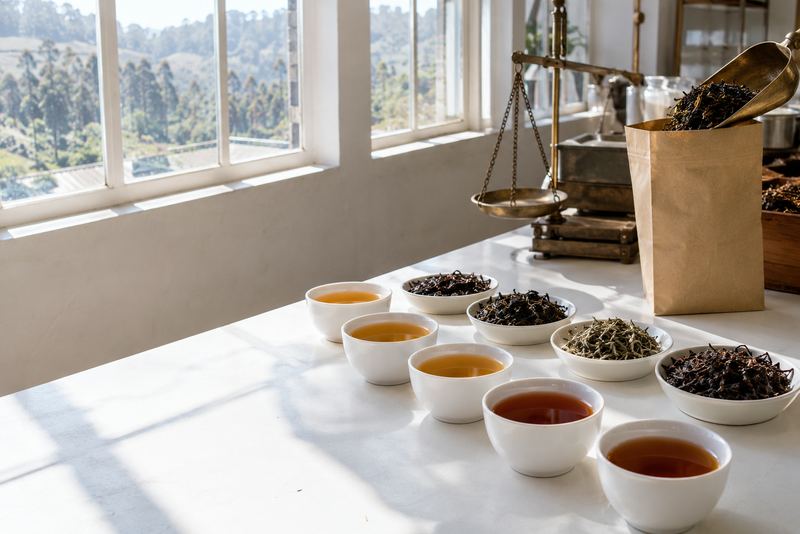 Tea cups, dry leaf and a pouch on a sunny tasting table