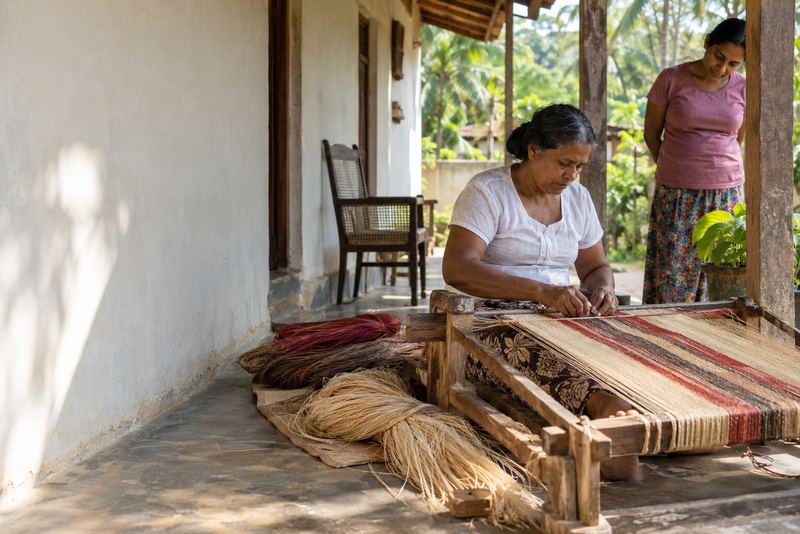 A weaver making a striped Dumbara mat on a village veranda