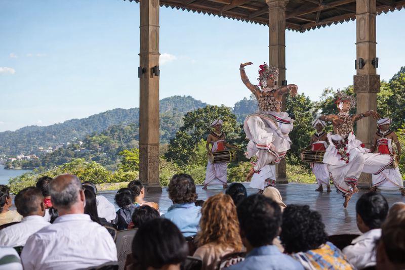 Kandyan dancers mid-leap in an open pavilion by day