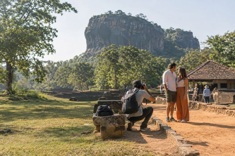 A hired photographer framing visitors below Sigiriya rock