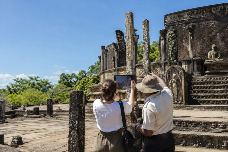 A visitor holding a tablet up to the Polonnaruwa Vatadage