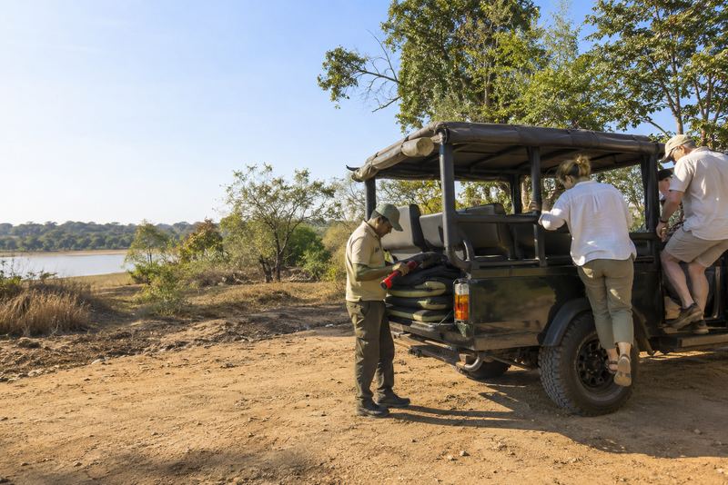 A guide readying a safari jeep with torches in afternoon sun
