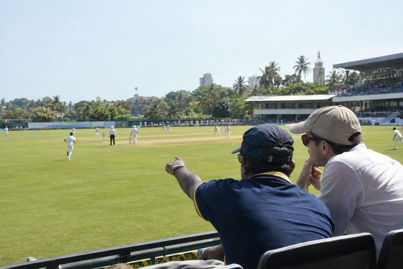 A local fan explaining a day cricket match to a visitor