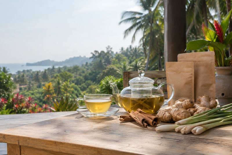 A glass teapot of herbal tea with cinnamon, lemongrass and ginger