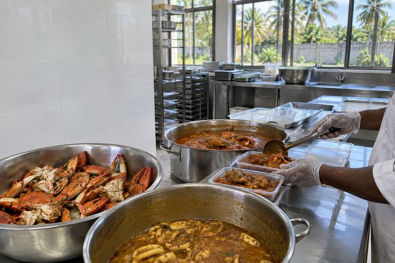 Crab curry being packed into chilled trays in a sunny Jaffna kitchen
