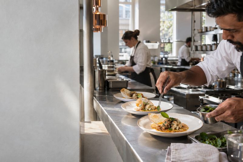 A chef plating crab curry and a hopper at a London restaurant pass