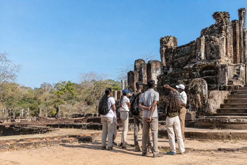 Trainee guides listening to an instructor at the Polonnaruwa ruins