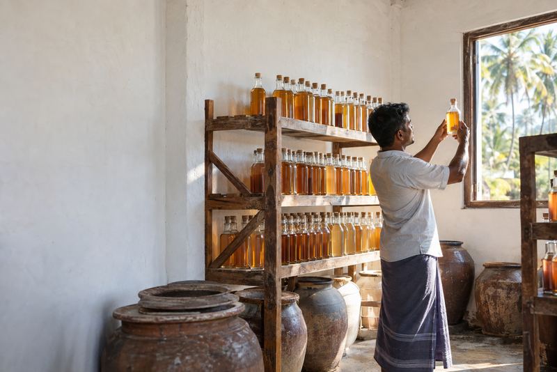 Bottles of coconut vinegar ageing on racks beside clay jars
