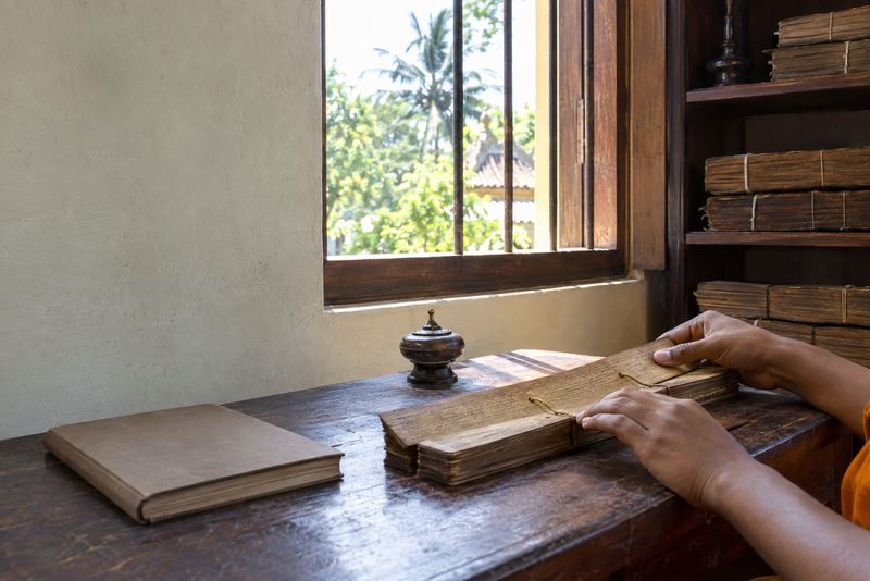 A student turning a palm-leaf manuscript in a temple library