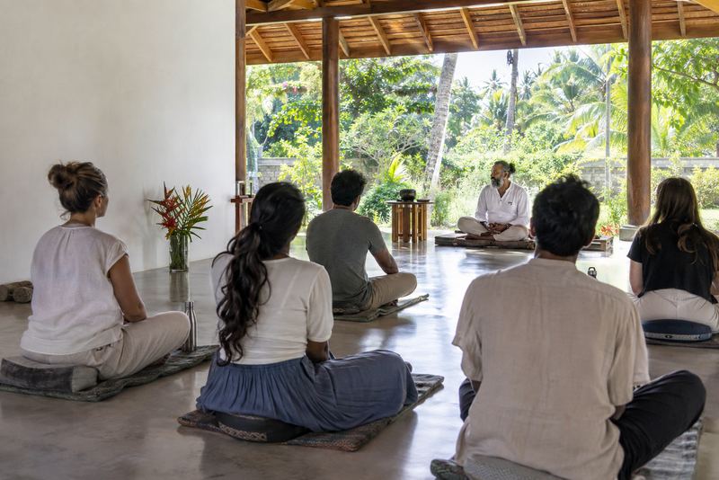 Trainee meditation instructors seated in an open hall in the morning