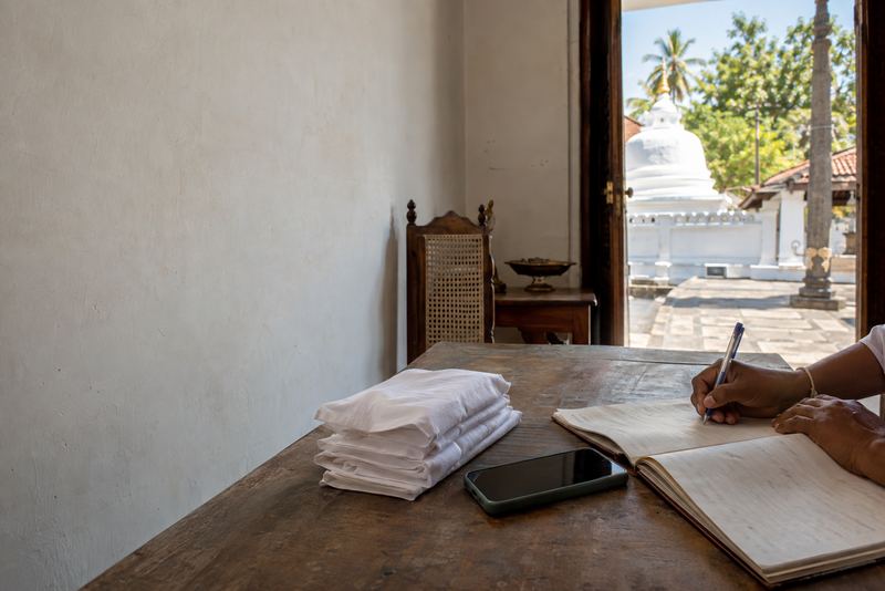 A volunteer writing bookings in a diary in a temple office