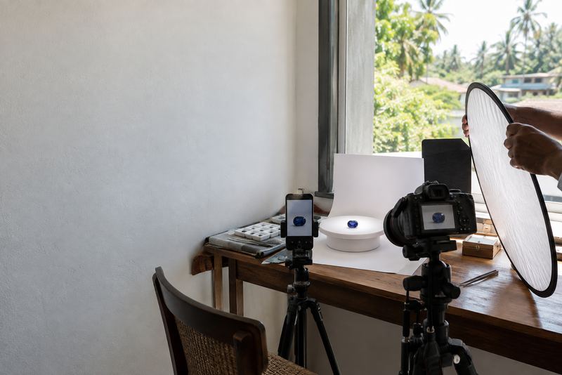 A dealer filming a sapphire on a turntable by a window