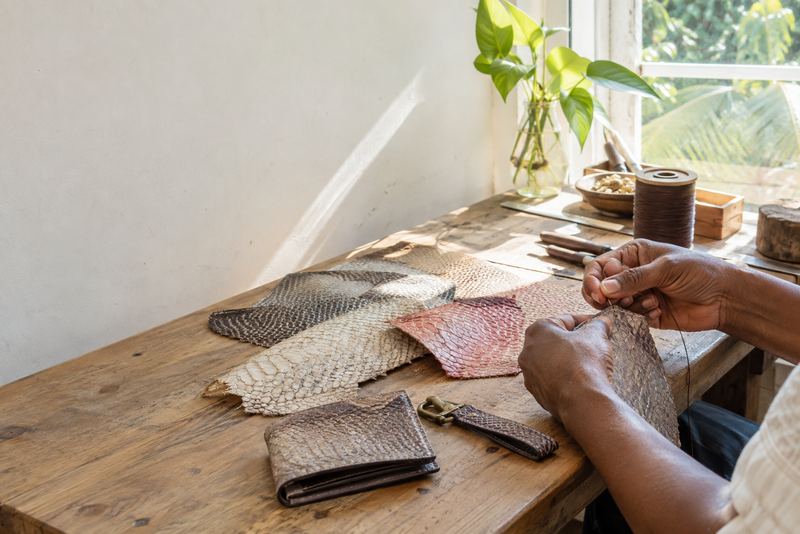 Fish leather goods being stitched on a pale workbench