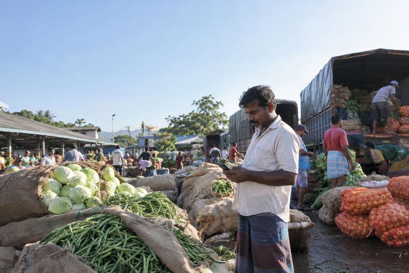 A farmer checking prices on his phone at a market
