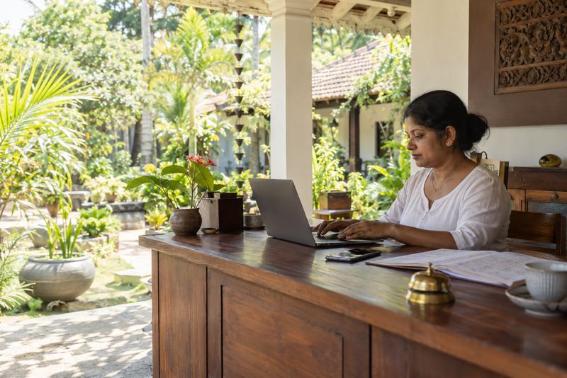 A guesthouse desk with a laptop and ledger in morning light
