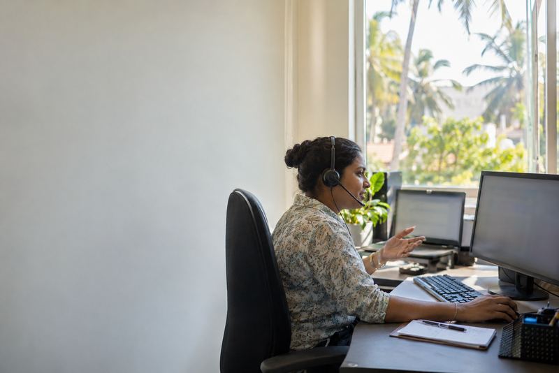A customer care worker on a call in a sunny office