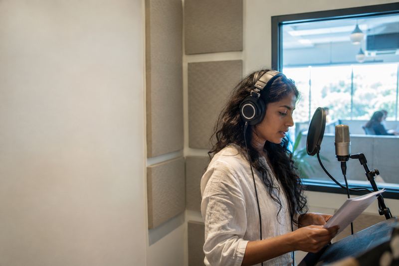 A speaker recording in a small booth with a microphone