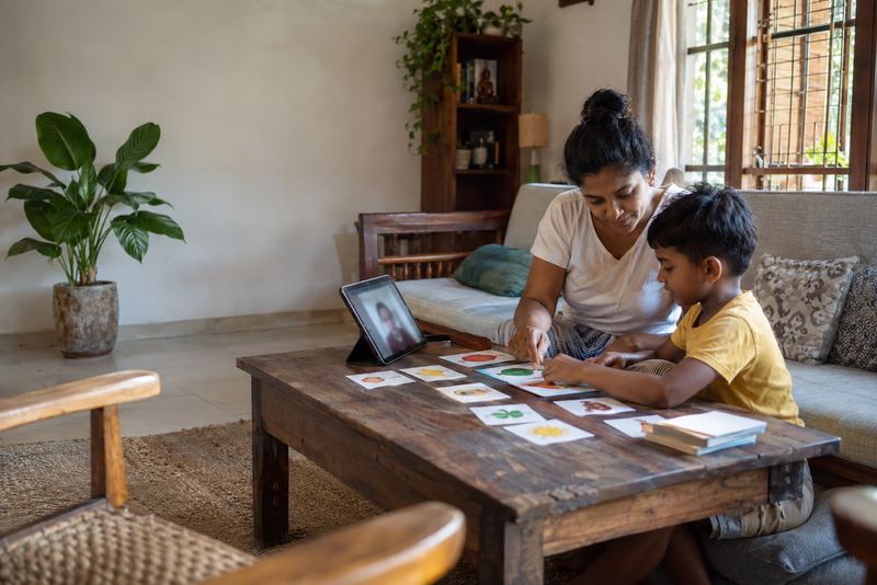 A child and helper with picture cards and a tablet