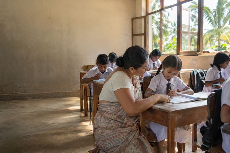 A visiting teacher helping a pupil in a classroom