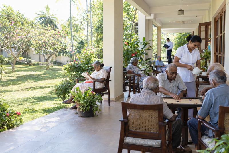 Elderly residents playing carrom on a sunny veranda