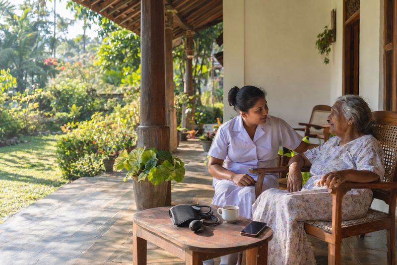 A nurse visiting an elderly person on a sunny veranda