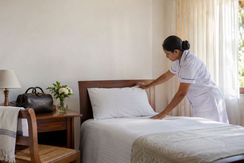 A nurse straightening a bed in a sunlit family bedroom