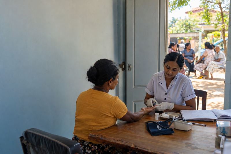 A nurse testing a patient's blood sugar at a clinic