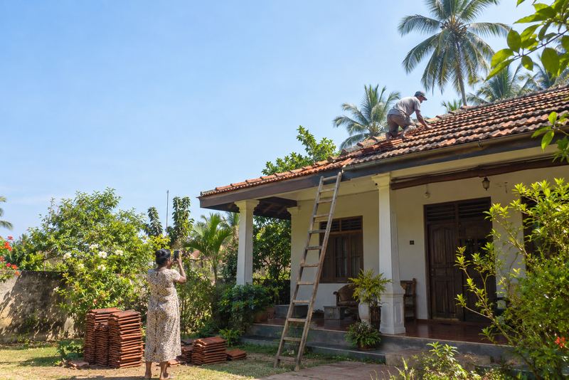 A builder fixing new clay roof tiles on a house