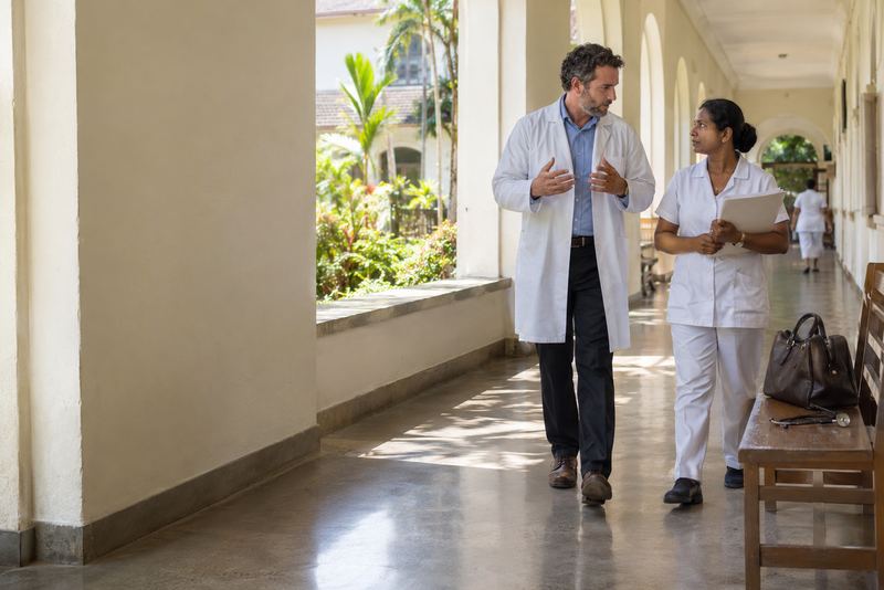 Two doctors walking a sunlit hospital corridor in Kandy
