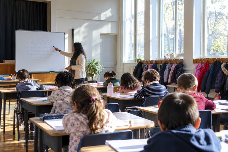 Children writing letters in a sunny Saturday school classroom