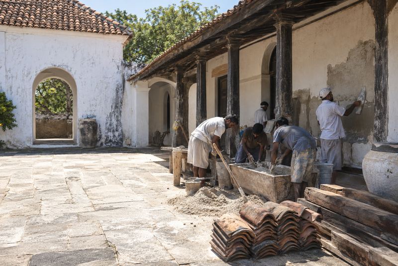 Apprentices learning lime plastering in a sunny courtyard