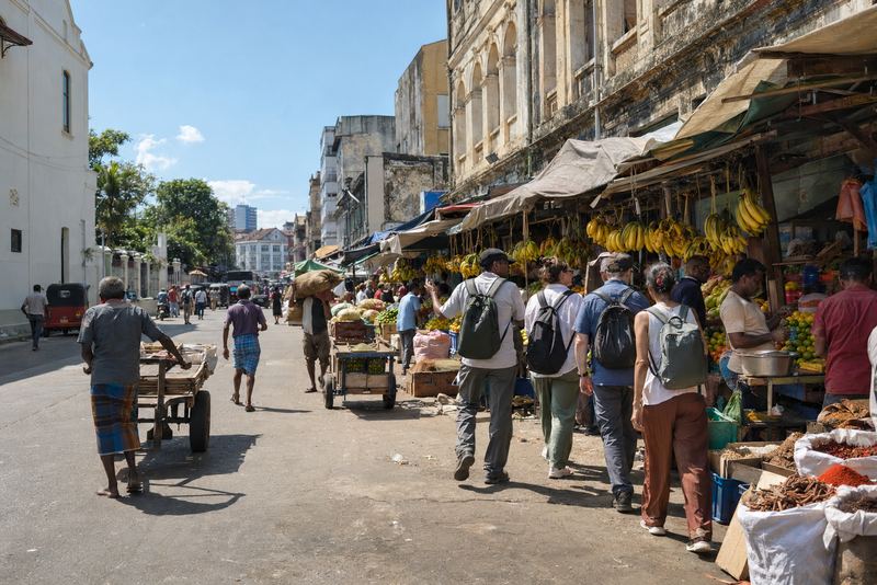 A walking tour moving through a sunny Pettah market street