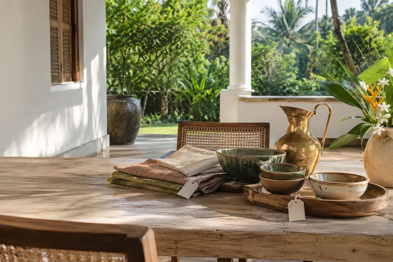 Ceramics, linen and brass arranged on a sunny veranda table