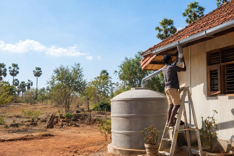 An installer fitting a rainwater tank at a dry-zone house