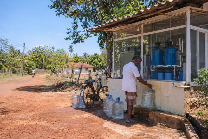 Clean water filled into cans at a sunny village kiosk