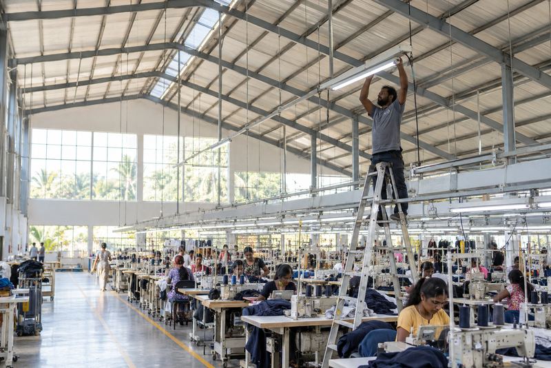 An electrician fitting LED lights over a factory floor