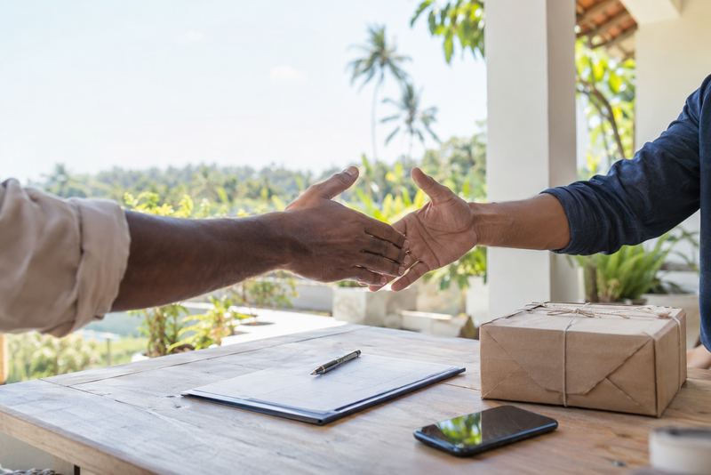 Two hands about to shake over a parcel and agreement