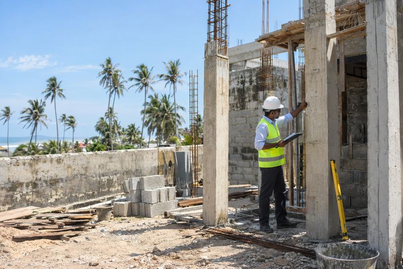 An inspector checking a half-built house in bright sun