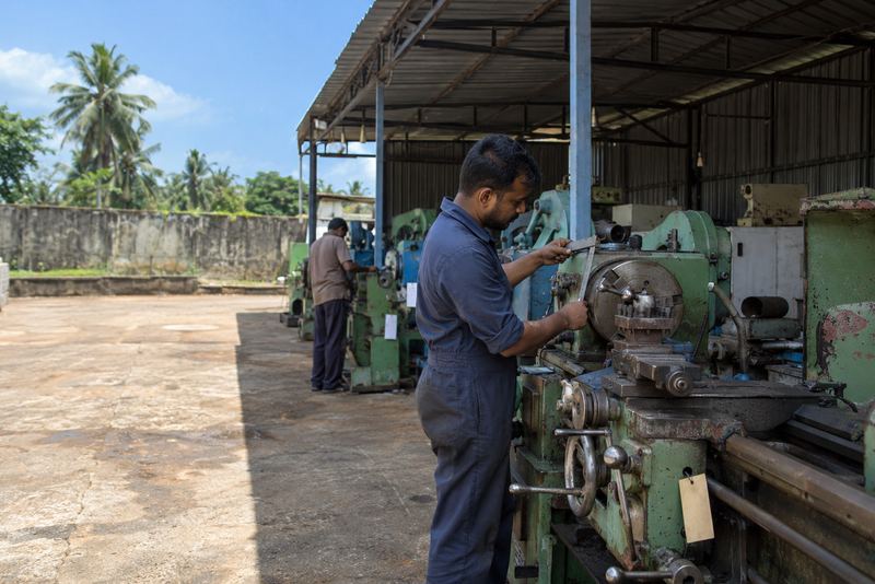 An inspector gauging a used lathe in a sunny yard