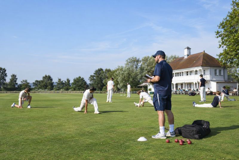 A coach leading training on a sunny English club ground