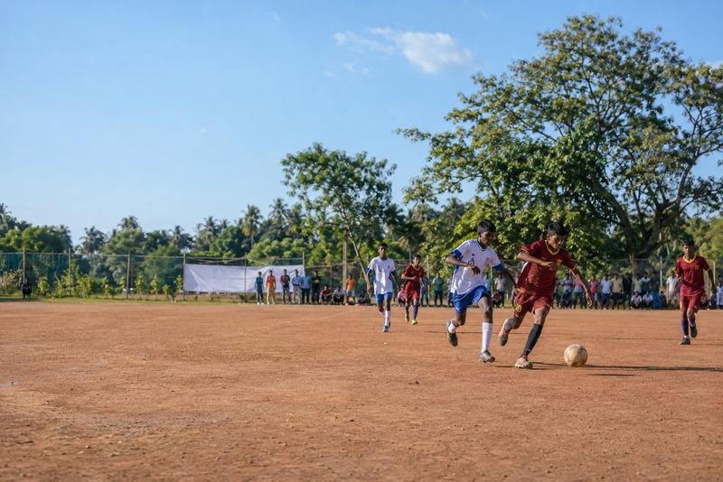 A school football match on a sunny red-earth ground