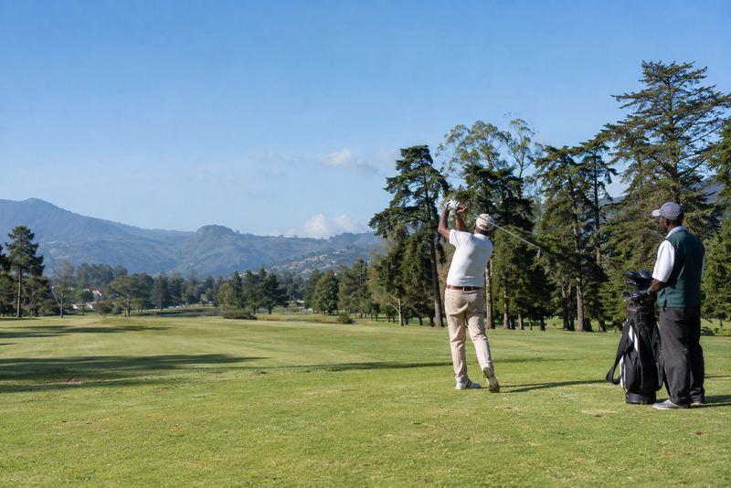 A golfer swinging on a sunny Nuwara Eliya fairway