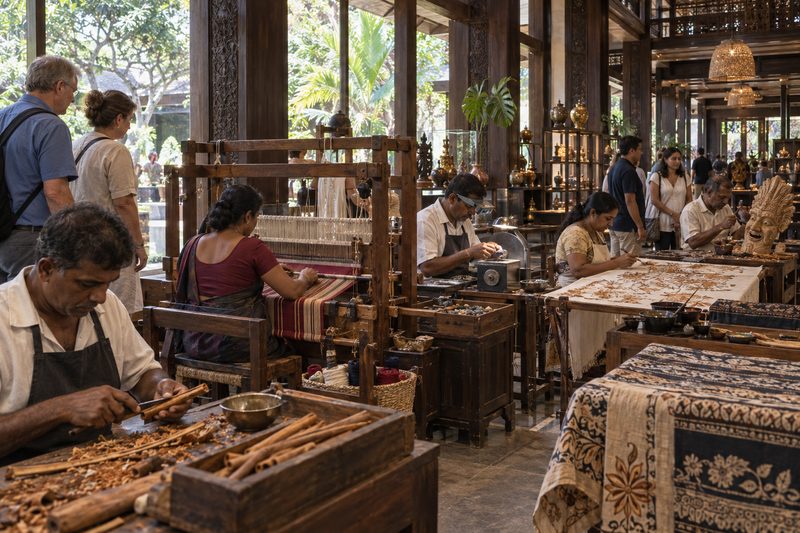 Makers at work in glass-fronted studios, watched by visitors